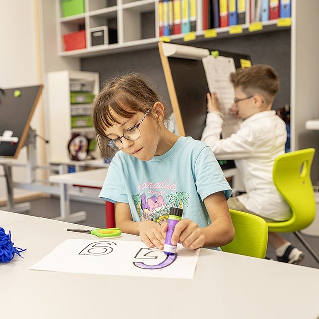 Drei Grundschüler sitzen im Klassenzimmer und arbeiten an ihren Aufgaben.